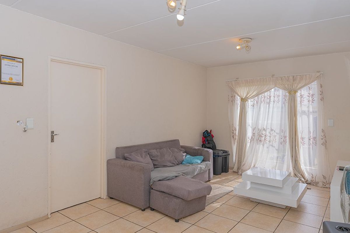 A living room featuring tiled flooring, neutral walls, and a sliding door providing natural light.
