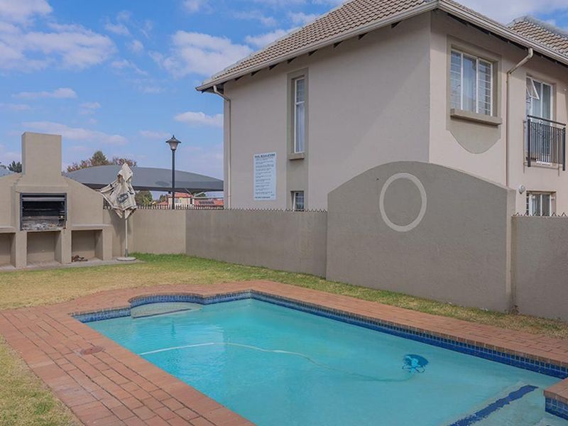 A private outdoor area featuring a swimming pool with brick coping, a built-in masonry braai, and a perimeter boundary wall.