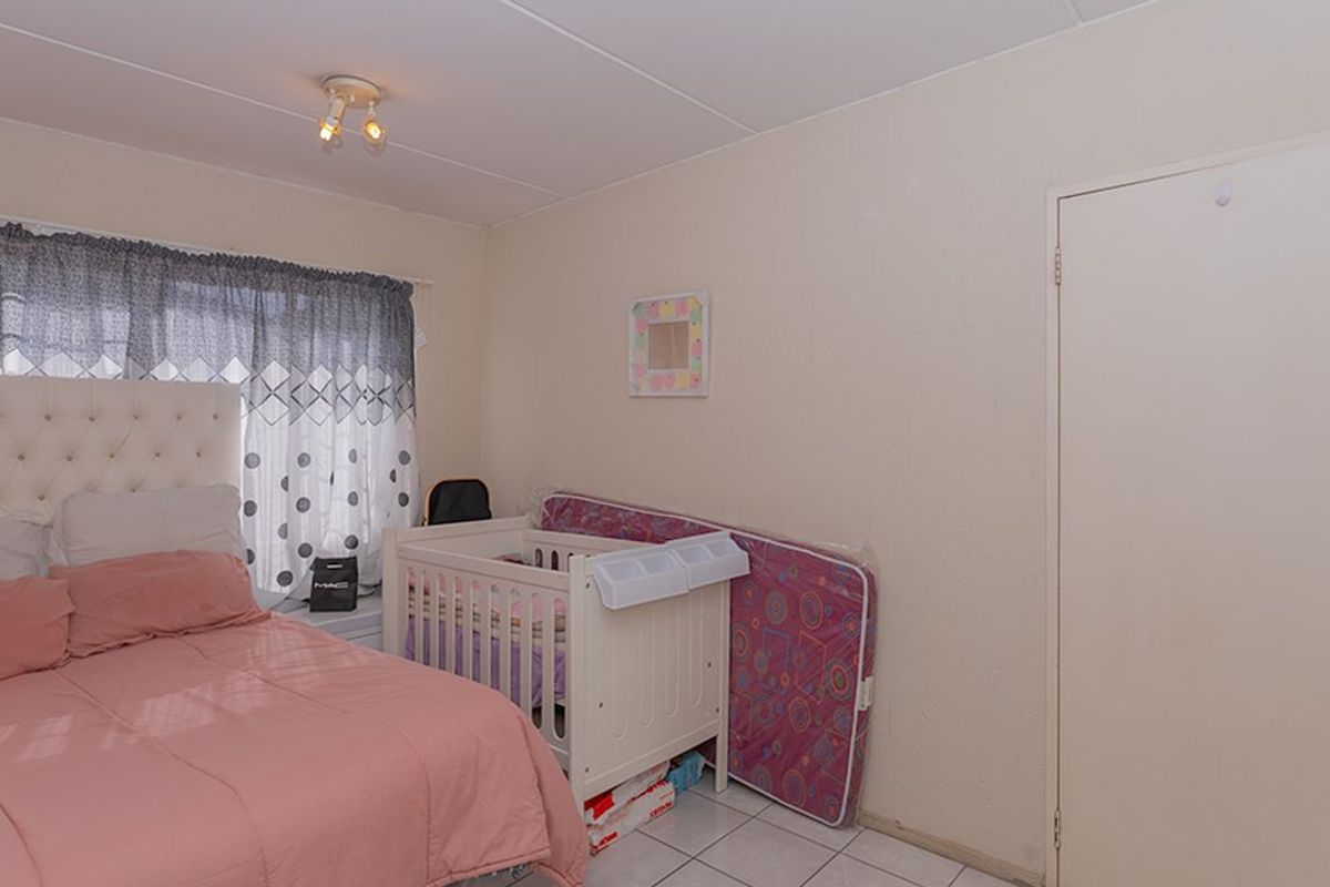 A functional bedroom featuring tiled flooring, a standard door, and a ceiling-mounted light fixture.