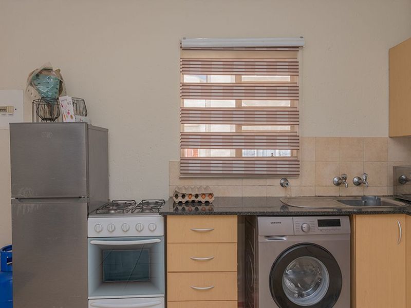 A functional kitchen featuring light wood cabinetry, granite countertops, a built-in gas stove, and integrated space for a washing machine.