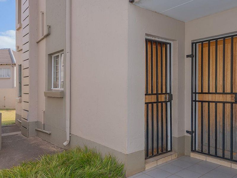 Exterior view of the apartment entrance featuring tiled flooring, security gates, and external wall lighting.