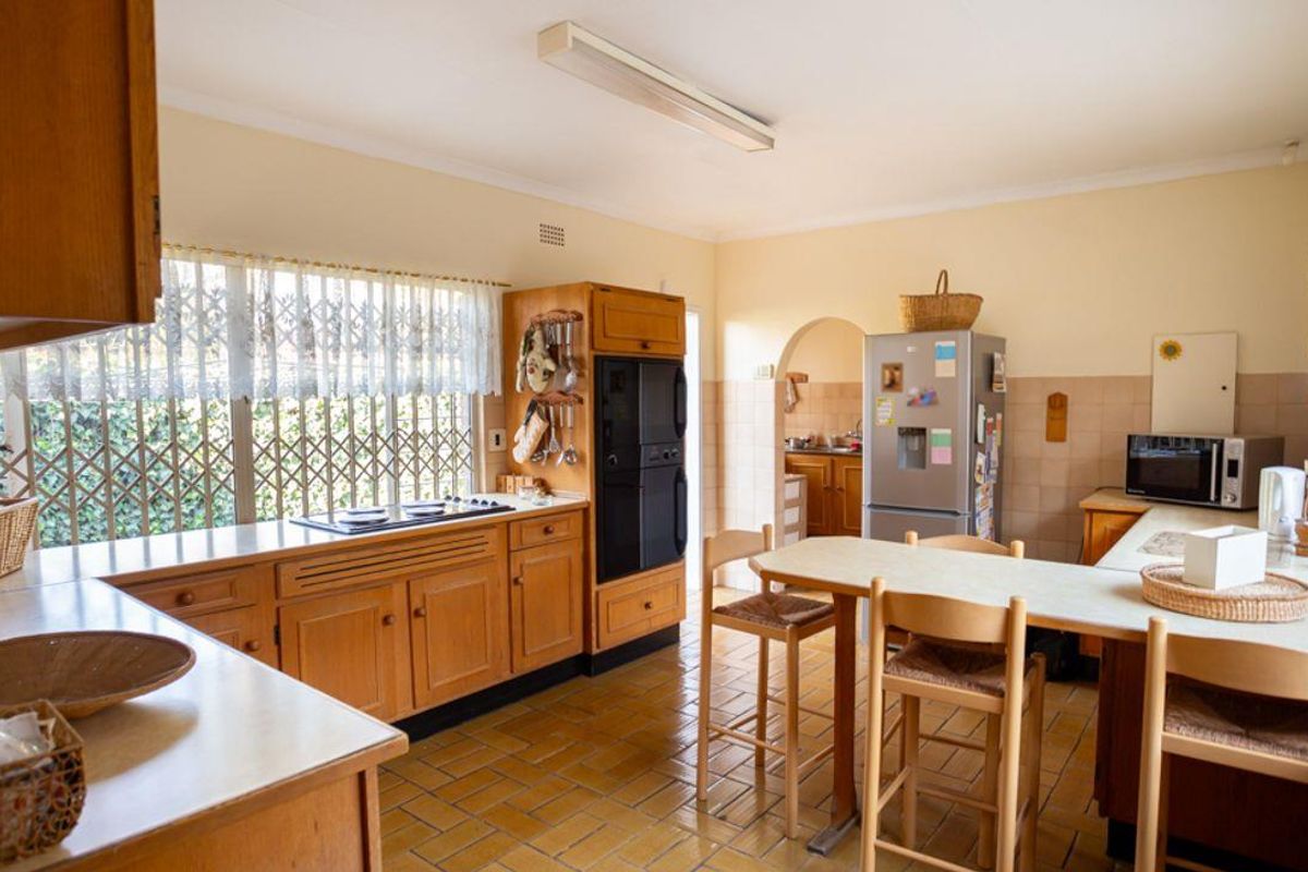 A spacious kitchen featuring wooden cabinetry, built-in oven, and tiled flooring, with an adjacent breakfast nook area.