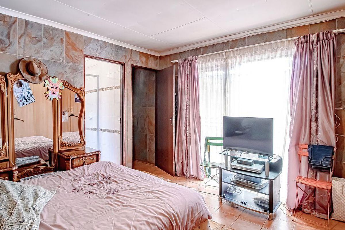 A bedroom featuring dated stone-look wall tiles, tiled flooring, and direct access to an outdoor area through sliding glass doors.