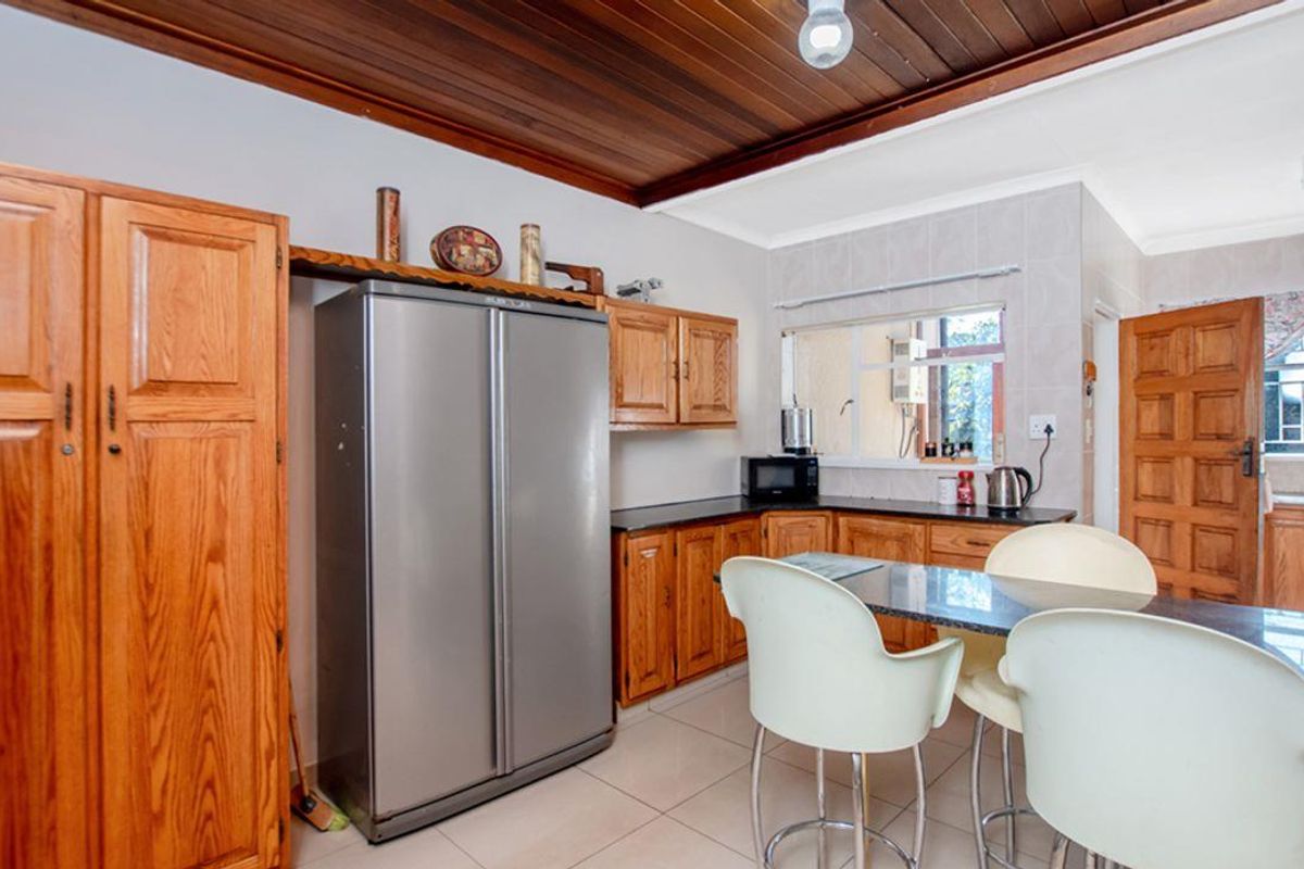 A functional kitchen featuring timber cabinetry, dark countertops, and a distinctive timber-paneled ceiling, offering a traditional aesthetic with practical layout.