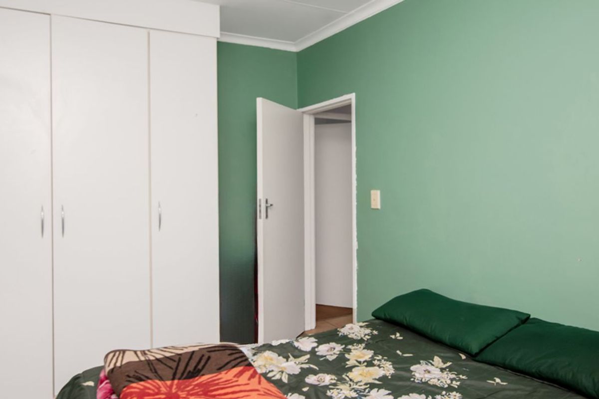 A bedroom featuring built-in white cabinetry and green painted walls, providing functional storage space.