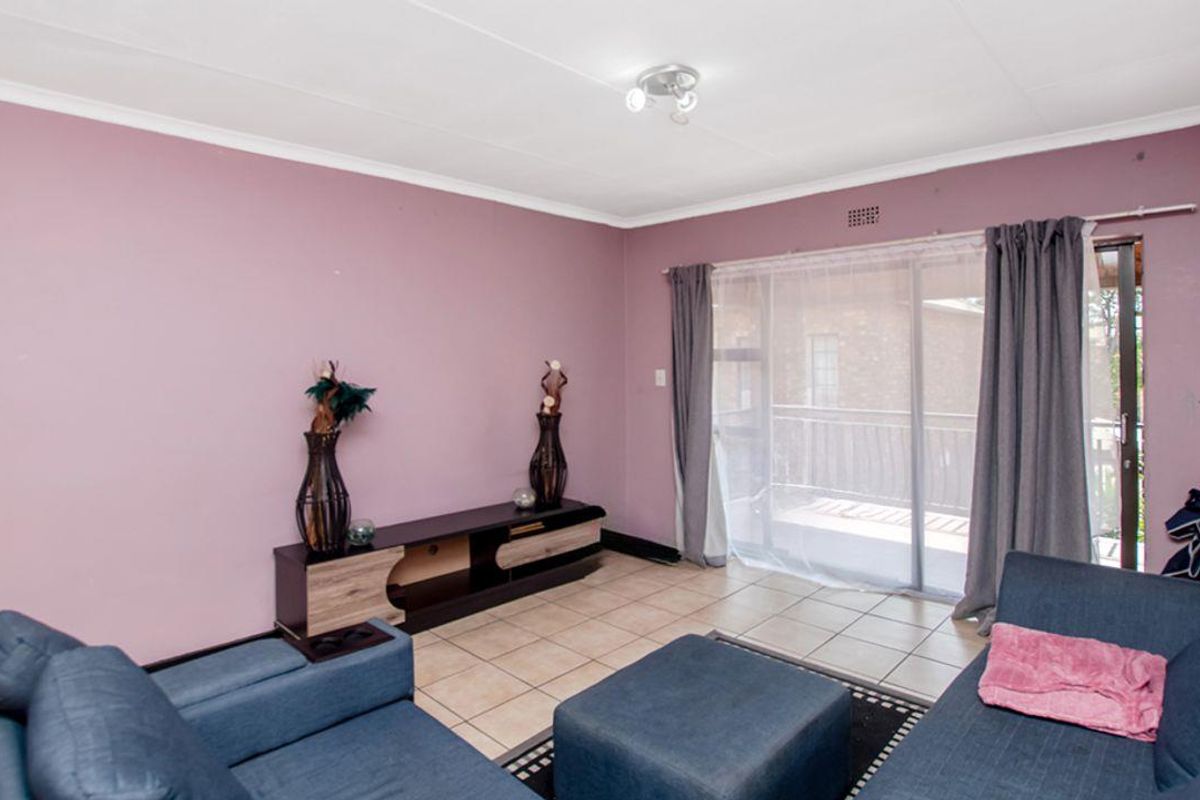 A living room featuring tiled flooring and a sliding glass door providing access to an outdoor balcony area.