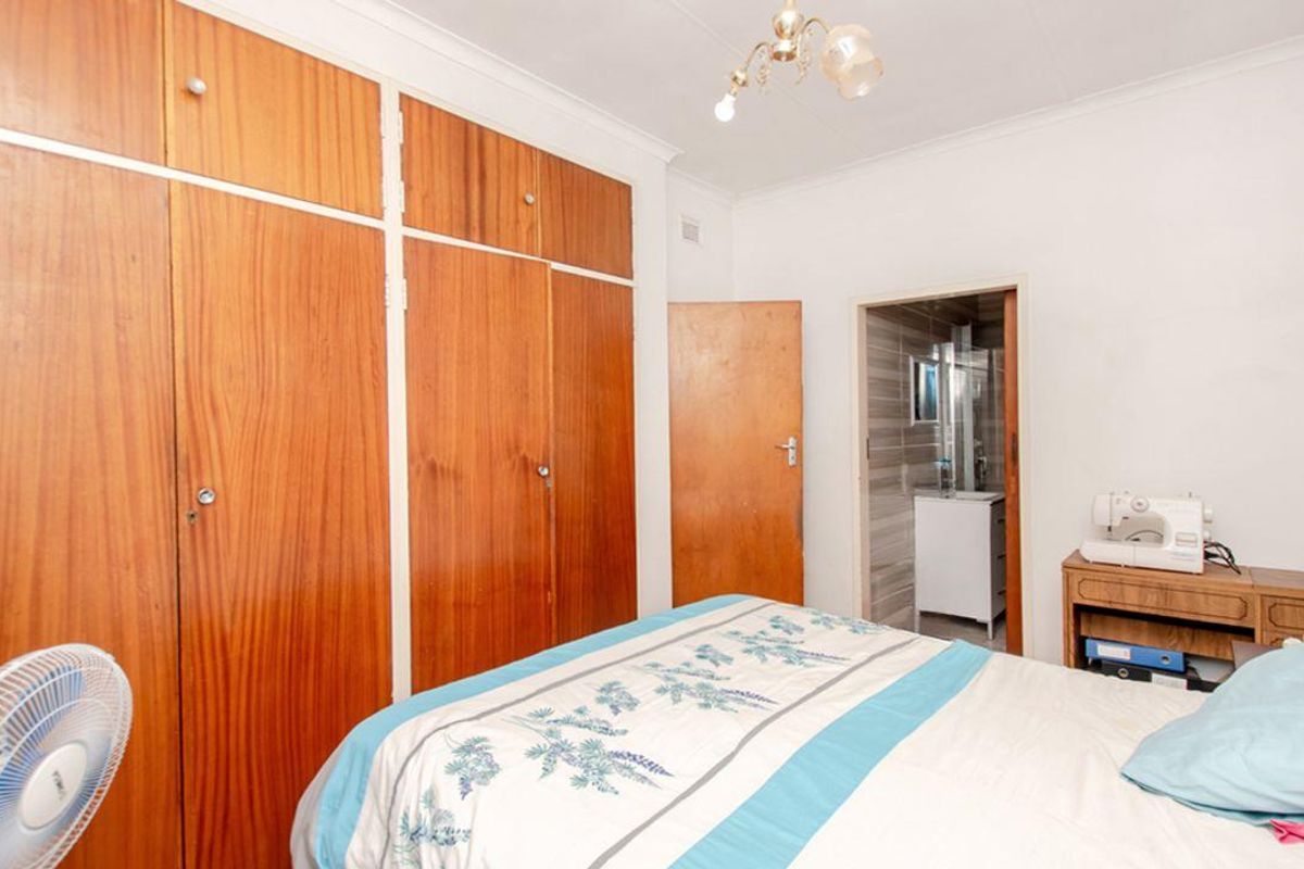 A bedroom featuring built-in wooden wardrobes and an en-suite bathroom access, showcasing a functional layout with traditional finishes.