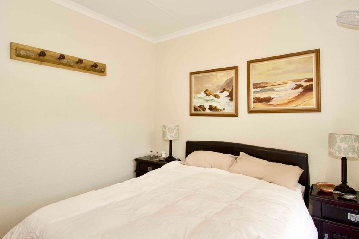 A well-maintained bedroom featuring neutral wall finishes, coved cornicing, and a ceiling-mounted fan.