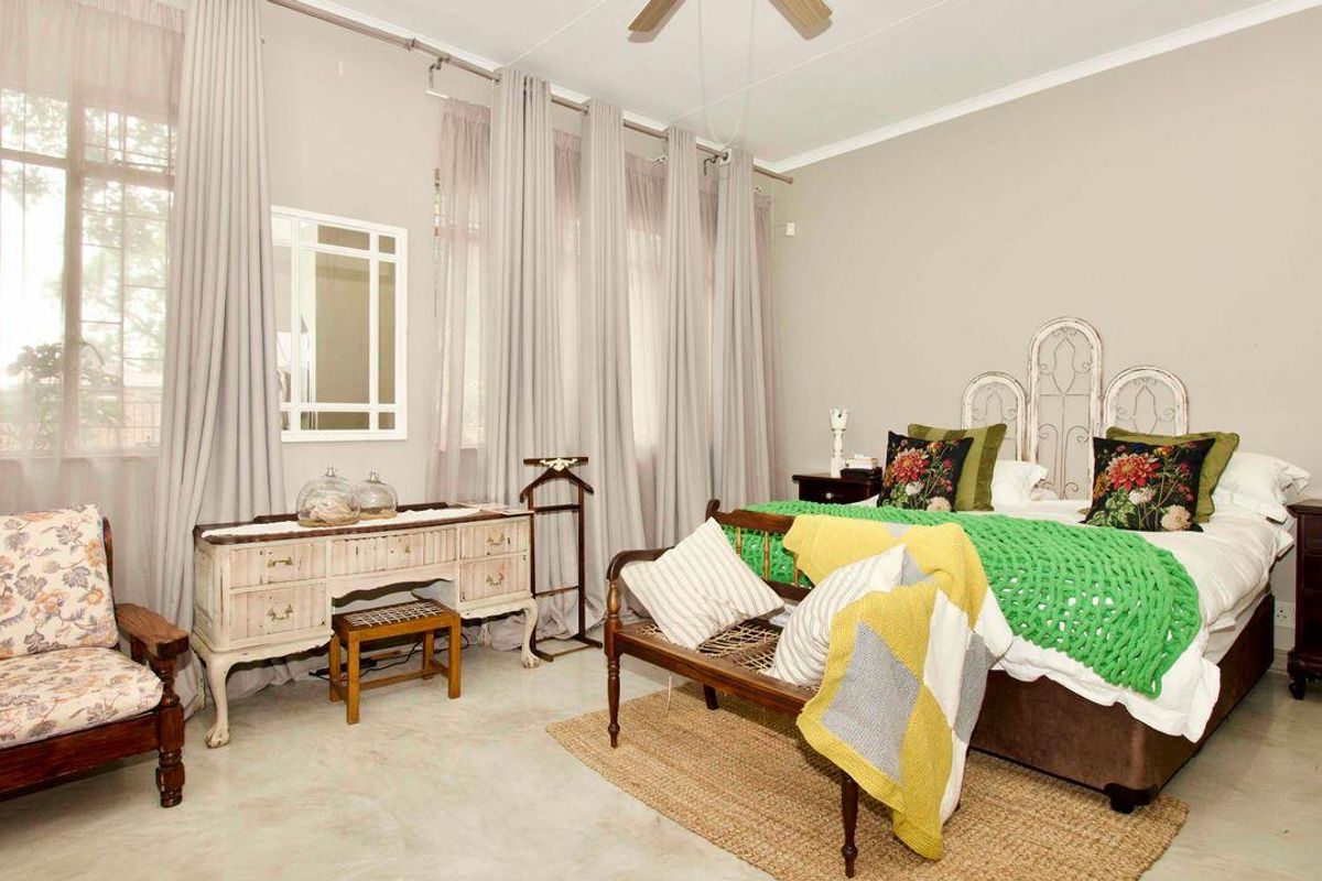 A spacious bedroom featuring large windows with floor-to-ceiling curtains, a ceiling fan, and polished concrete flooring.