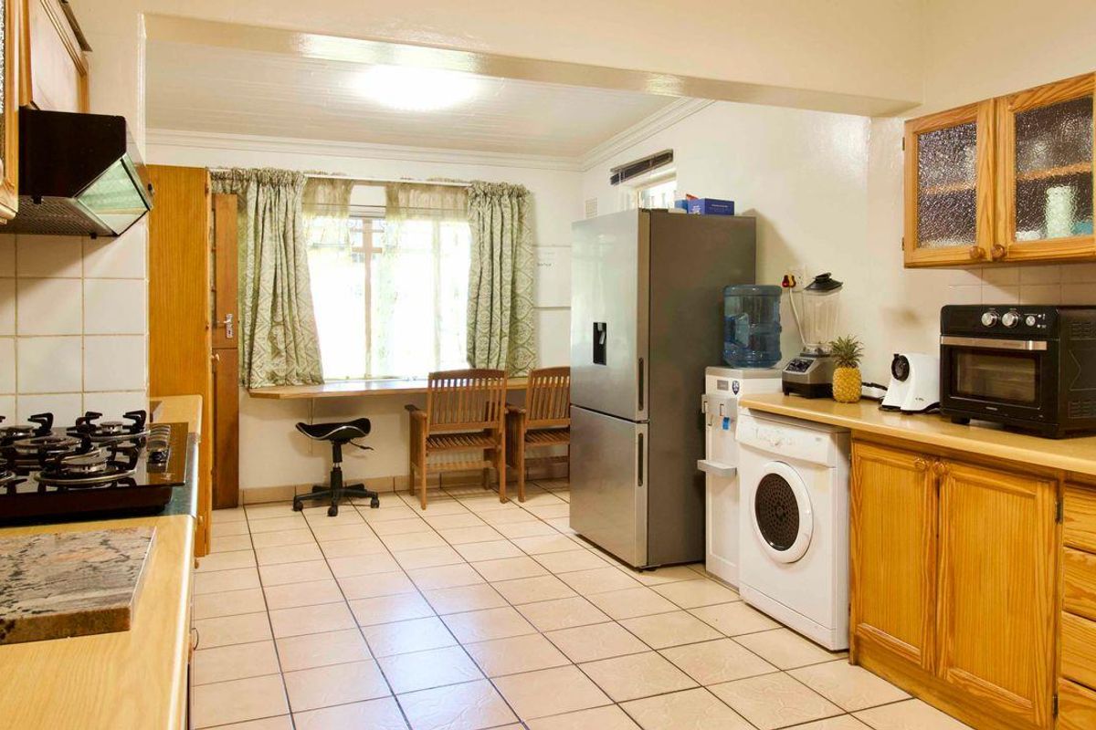 A functional kitchen featuring wooden cabinetry, tiled flooring, a built-in gas hob, and an integrated breakfast nook area.