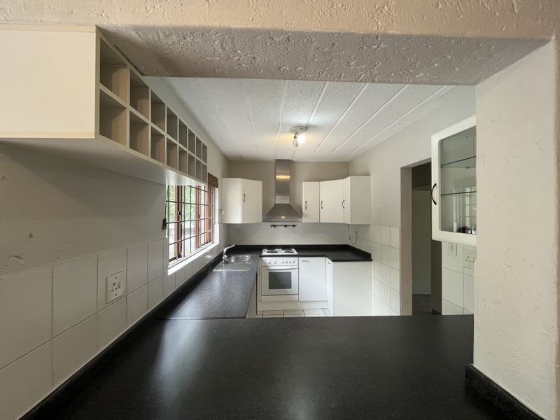 A functional kitchen featuring white cabinetry, dark laminate countertops, a built-in stove with extractor fan, and a tiled backsplash.