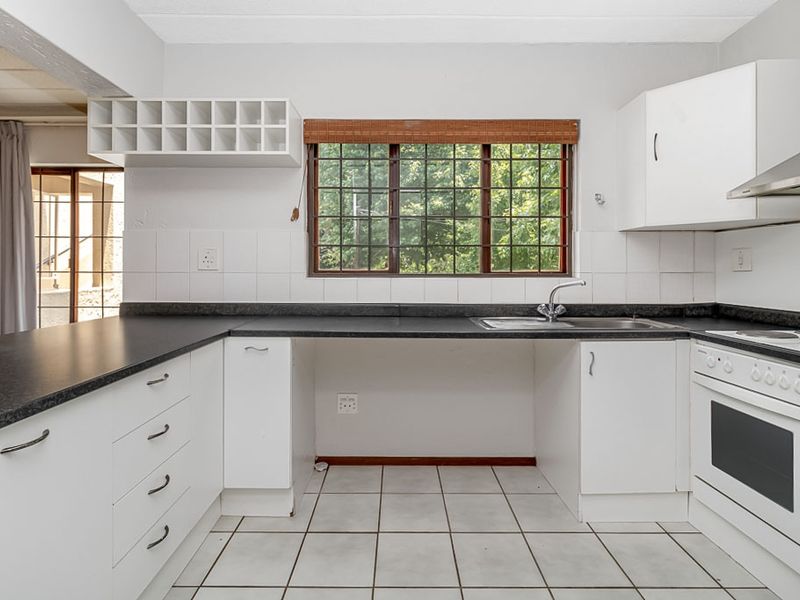 A functional kitchen featuring white cabinetry, dark laminate countertops, a built-in oven with hob, and tiled flooring, offering a clean and practical workspace.