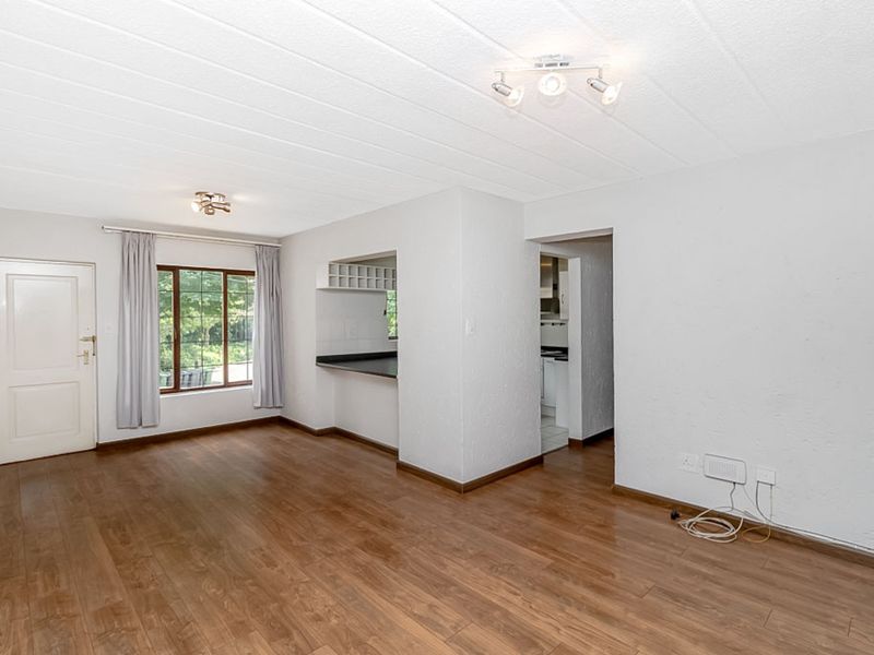 Spacious open-plan living area featuring laminate flooring, a built-in breakfast bar, and direct access to the kitchen, offering a versatile layout.
