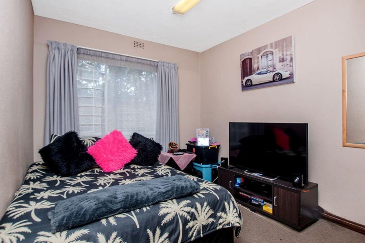 A standard bedroom featuring a window with curtain tracks and a ceiling-mounted light fixture.
