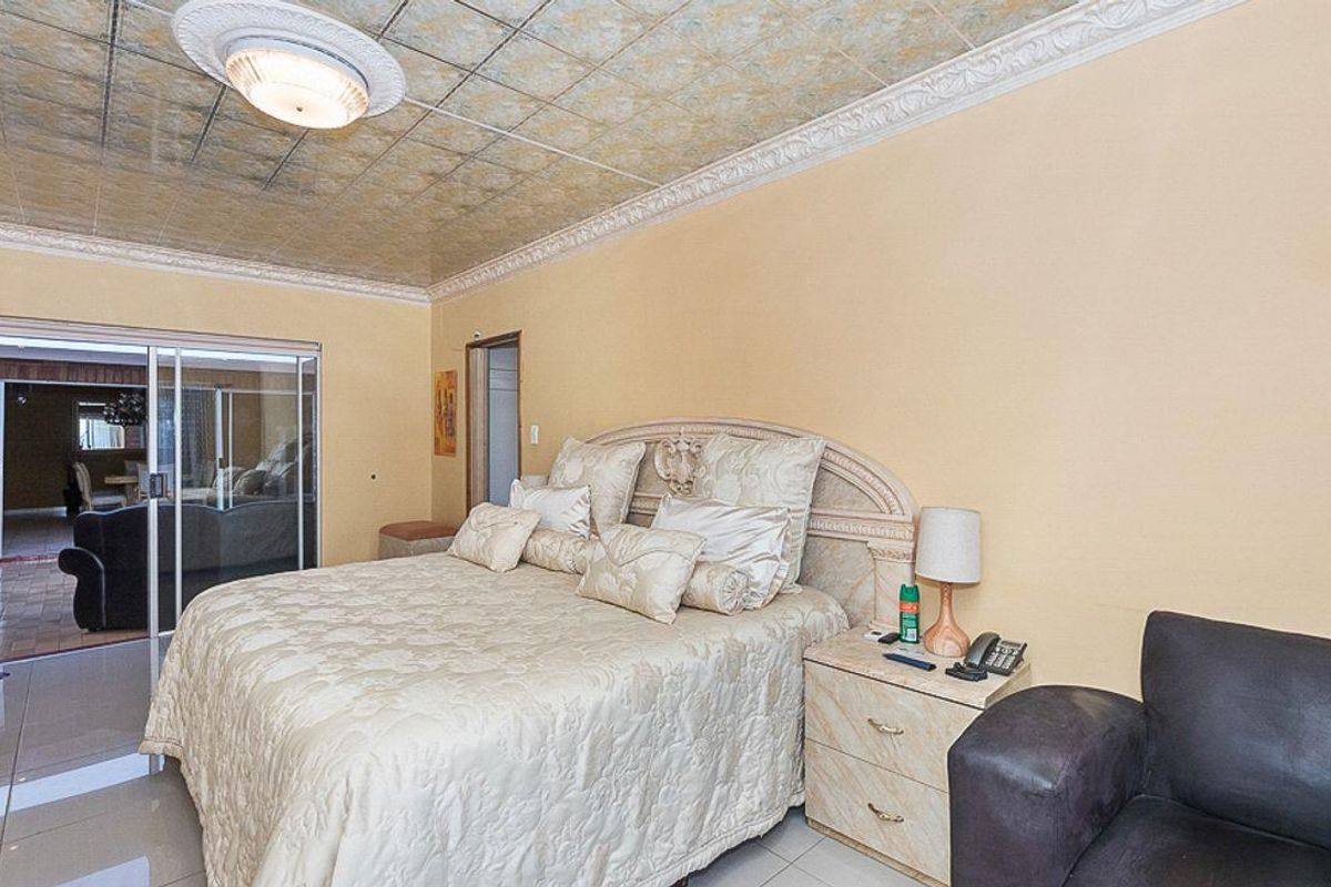 Spacious bedroom featuring tiled flooring, decorative ceiling tiles, and sliding glass doors leading to an adjacent living area.
