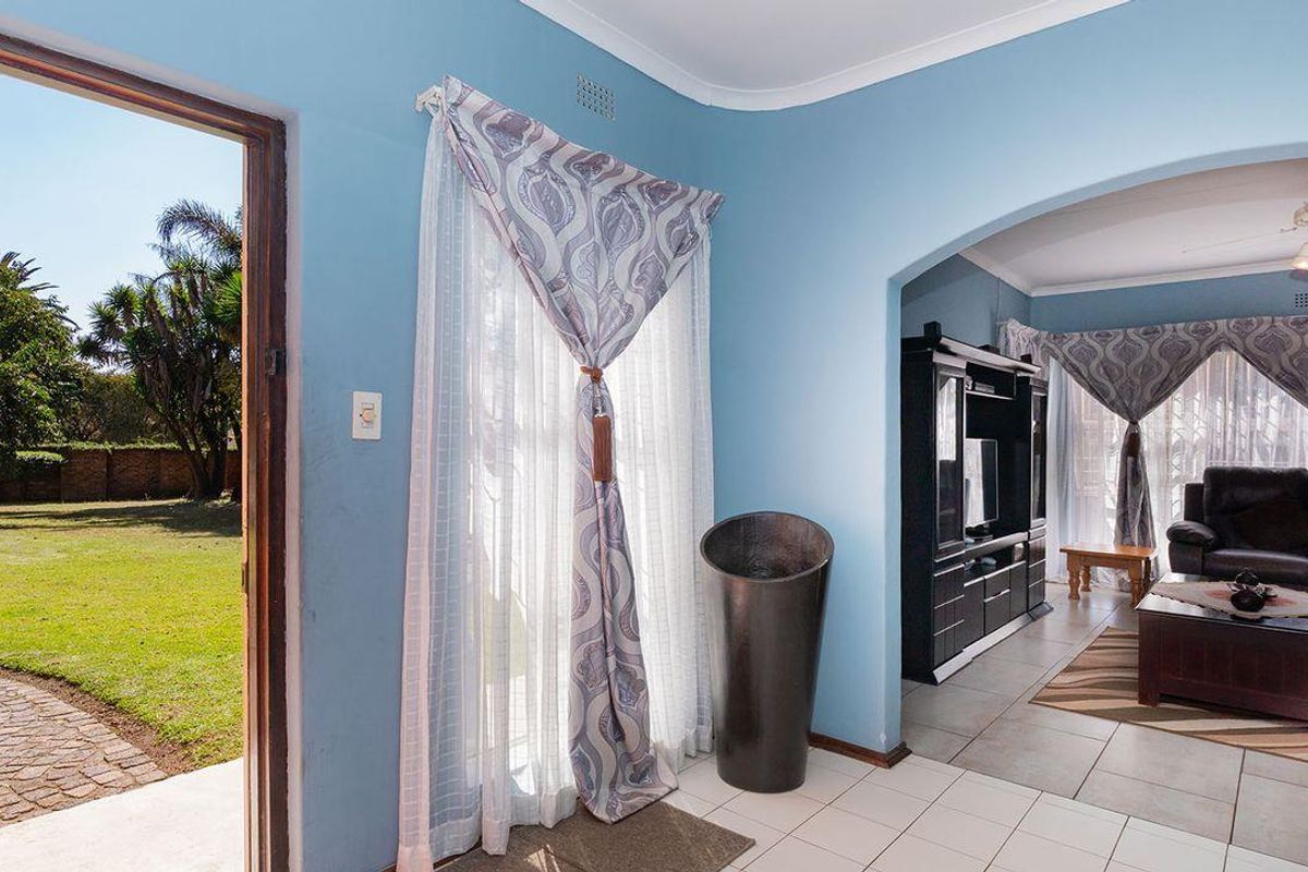 A bright living area featuring tiled flooring, an arched entryway, and direct access to a private garden through a glass door.