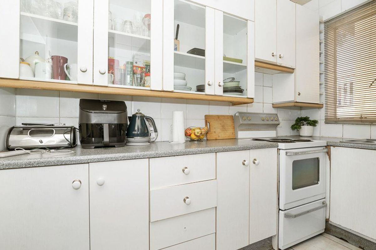A compact kitchen featuring white cabinetry, laminate countertops, and a built-in oven, offering a functional layout with potential for modern updates.