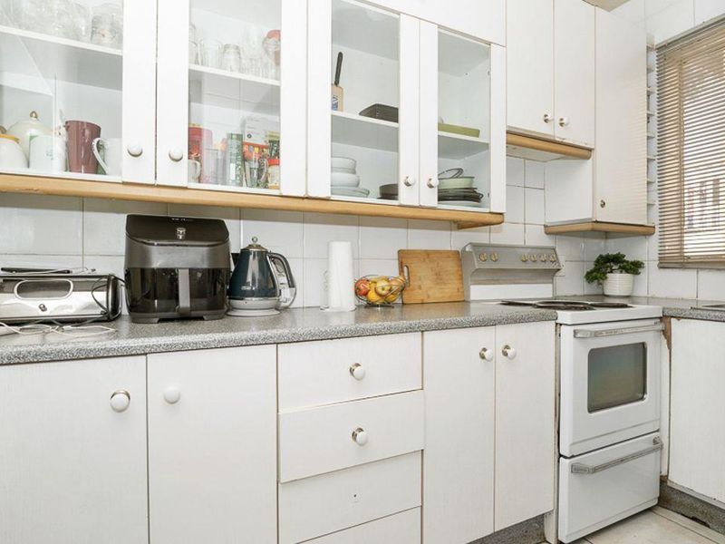 A compact kitchen featuring white cabinetry, laminate countertops, and a built-in oven, offering a functional layout with potential for modern updates.