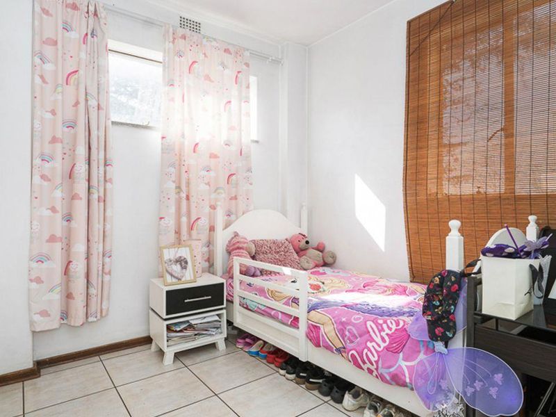 A functional bedroom featuring tiled flooring and natural light through a window, providing a neutral base for personalization.