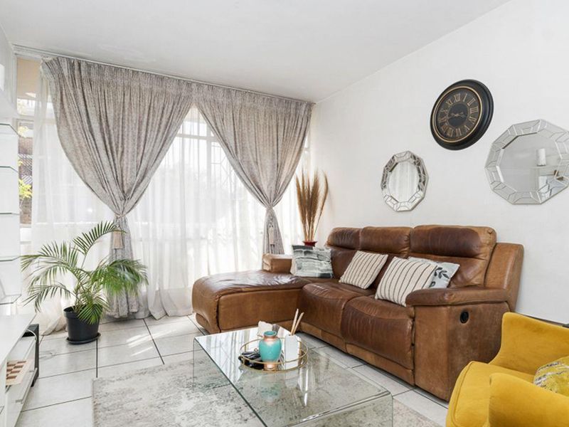 A bright living room featuring tiled flooring and a built-in shelving unit, offering a comfortable and well-maintained space.