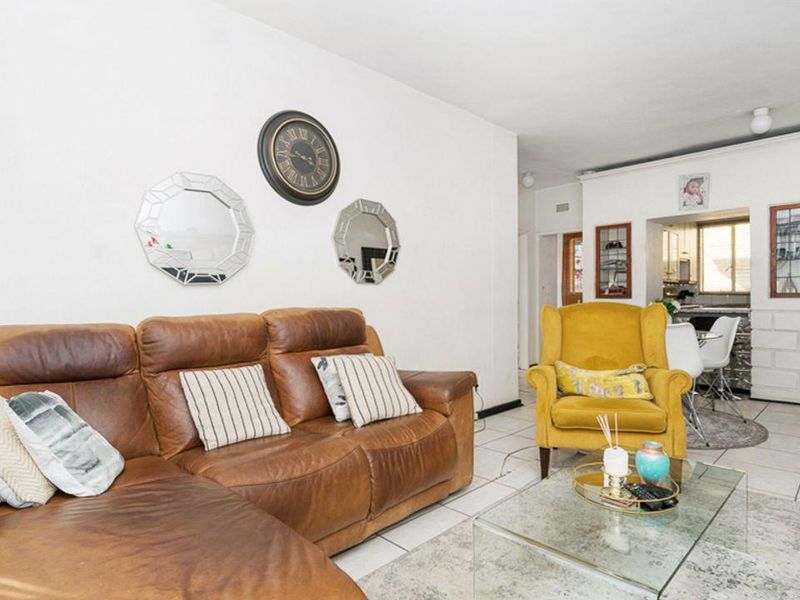 Open plan living area featuring tiled flooring and a connected kitchen space with built-in cabinetry.