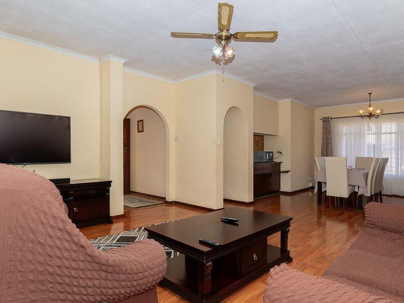 Spacious open-plan living and dining area featuring laminate flooring, coved cornicing, and classic archway transitions between rooms.