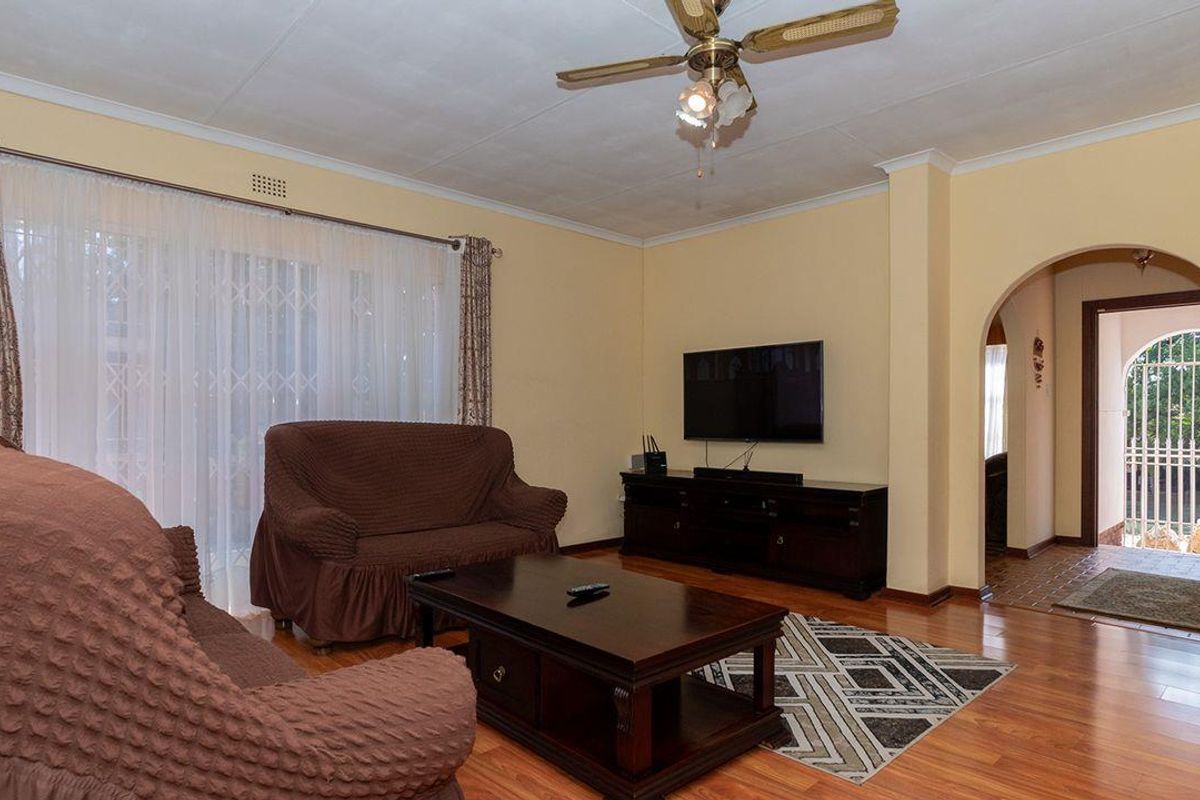 A comfortable living room featuring laminate flooring, a ceiling fan, and an arched entryway leading to an exterior door.