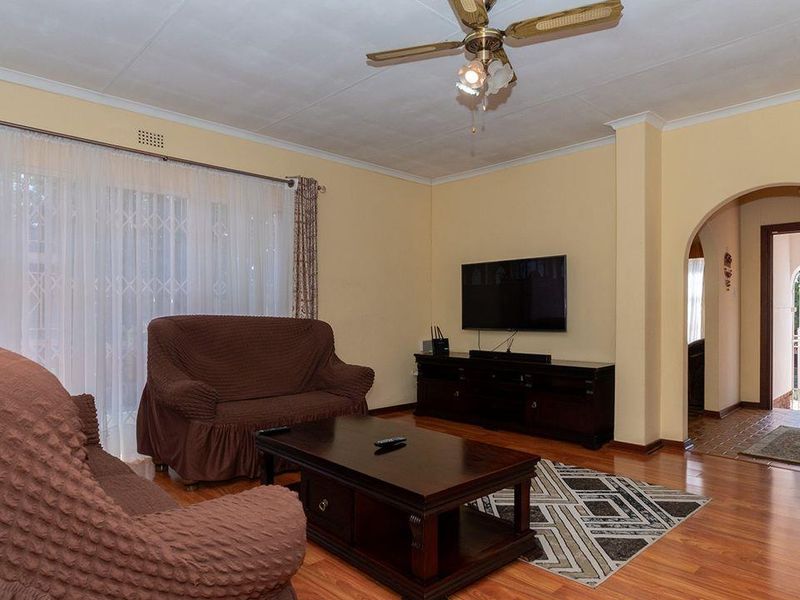 A comfortable living room featuring laminate flooring, a ceiling fan, and an arched entryway leading to an exterior door.