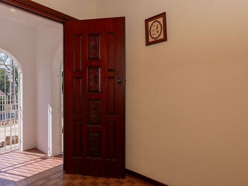 Entrance area featuring a solid timber door, tiled flooring, and an arched security gate leading to the exterior.