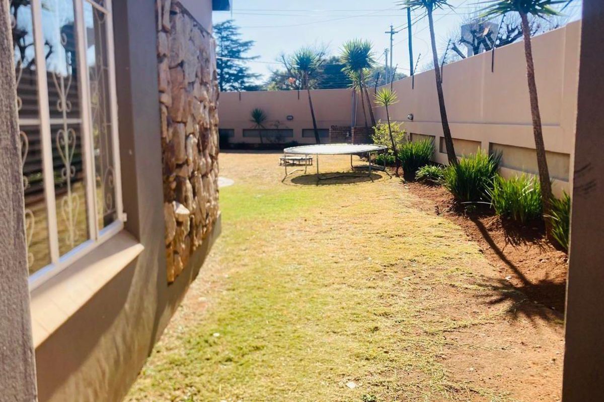 A view of the rear garden area featuring stone cladding on the exterior wall and a perimeter boundary wall.