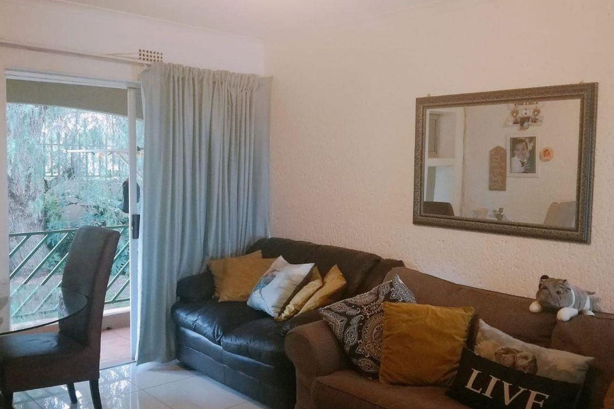 A living room featuring tiled flooring and a sliding glass door providing access to an outdoor balcony area.