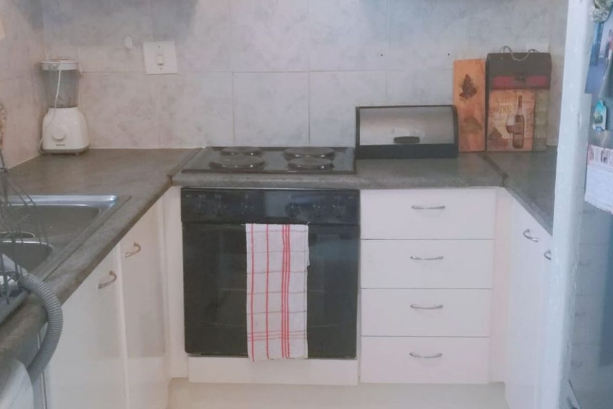 Compact kitchen featuring white cabinetry, a built-in oven with hob, and tiled backsplash, providing a functional workspace.