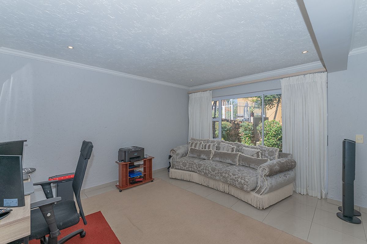 A living room featuring tiled flooring, recessed downlighting, and a large sliding glass door providing natural light and access to the exterior.