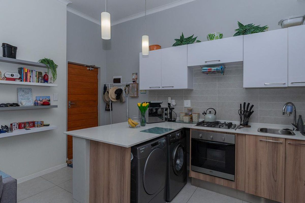 Modern kitchen featuring light wood and white cabinetry, stone countertops, integrated gas hob, built-in oven, and a tiled backsplash with convenient under-counter appliance space.