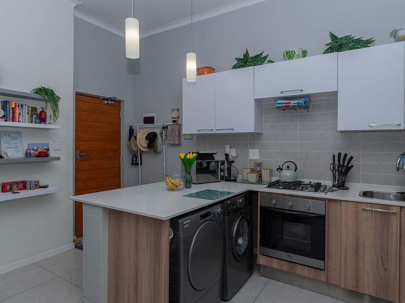 Modern kitchen featuring light wood and white cabinetry, stone countertops, integrated gas hob, built-in oven, and a tiled backsplash with convenient under-counter appliance space.