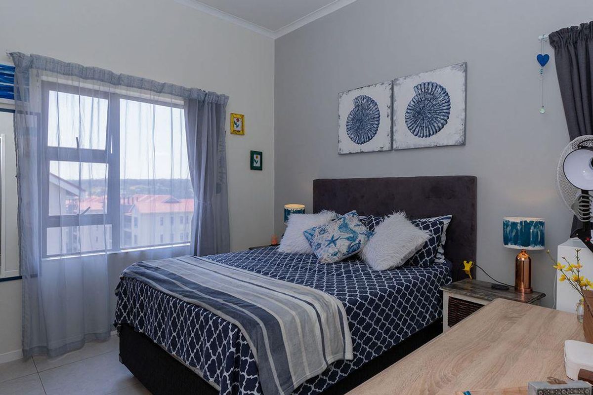 A well-maintained bedroom featuring tiled flooring, neutral wall tones, and a large window providing natural light.
