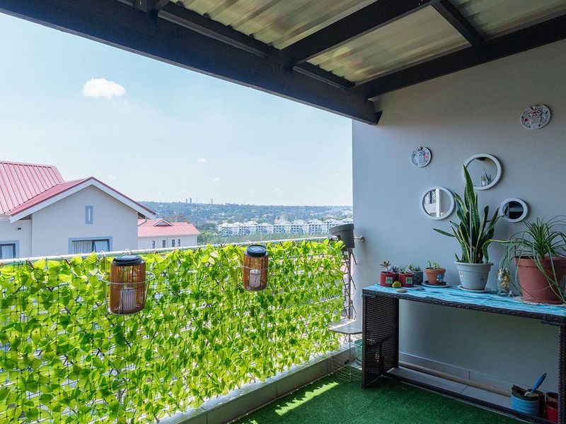 A covered balcony featuring artificial grass flooring, metal railings, and an open view of the surrounding neighborhood.