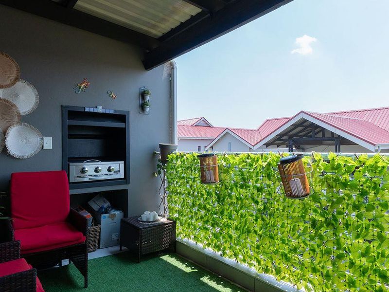 A covered balcony featuring a built-in braai and railing, providing an outdoor entertainment space with views of the surrounding residential area.