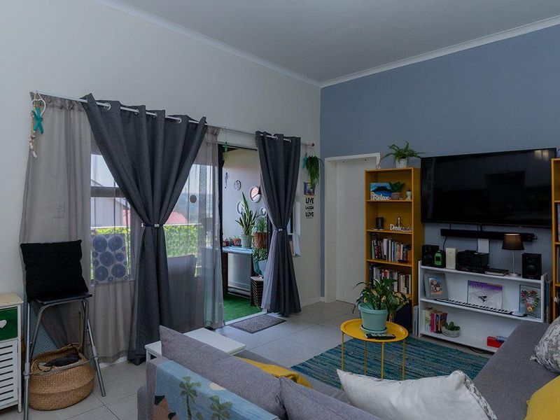 A living room featuring tiled flooring and a sliding glass door providing access to an outdoor balcony area.