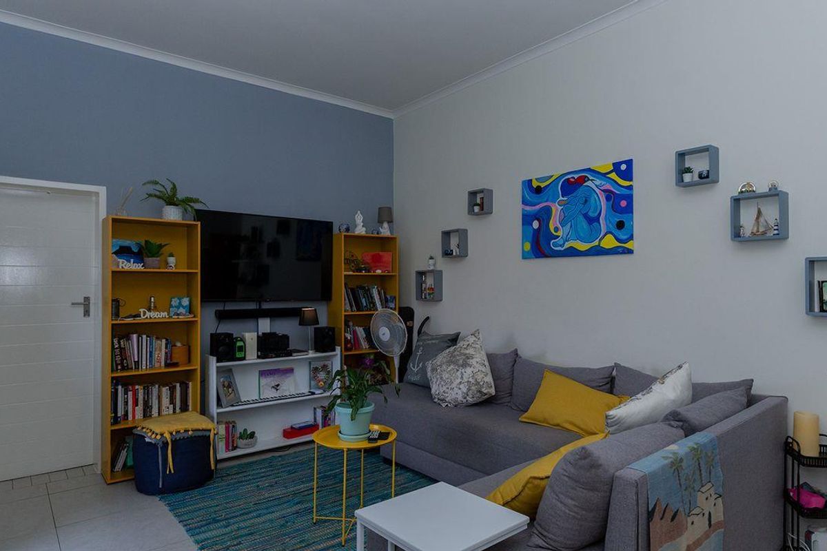 A comfortable living room featuring tiled flooring, neutral wall finishes, and a coved ceiling, providing a functional and well-maintained living space.