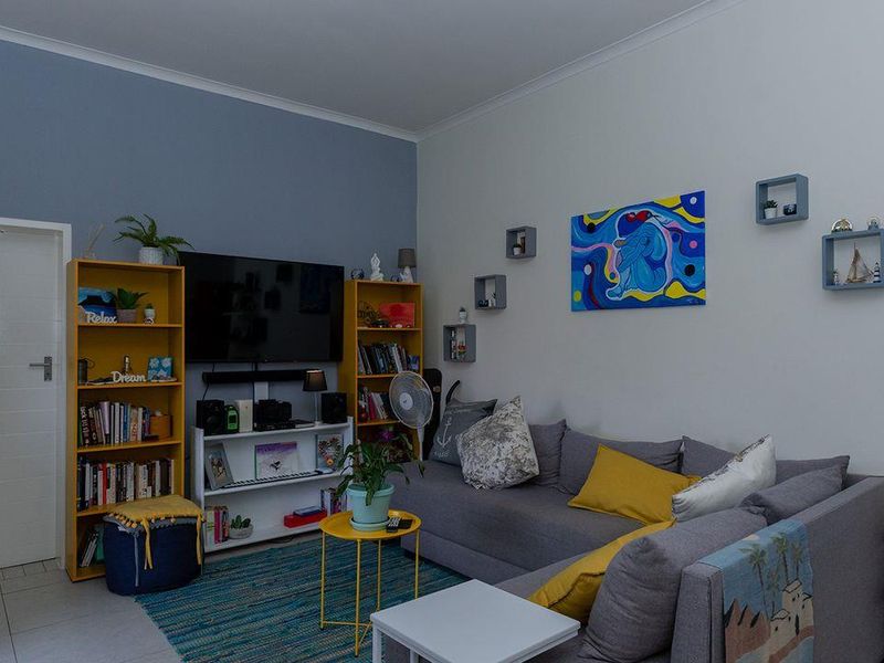 A comfortable living room featuring tiled flooring, neutral wall finishes, and a coved ceiling, providing a functional and well-maintained living space.