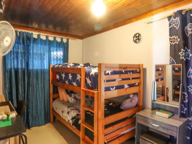 A bedroom featuring a timber-clad ceiling and a security gate on the window.