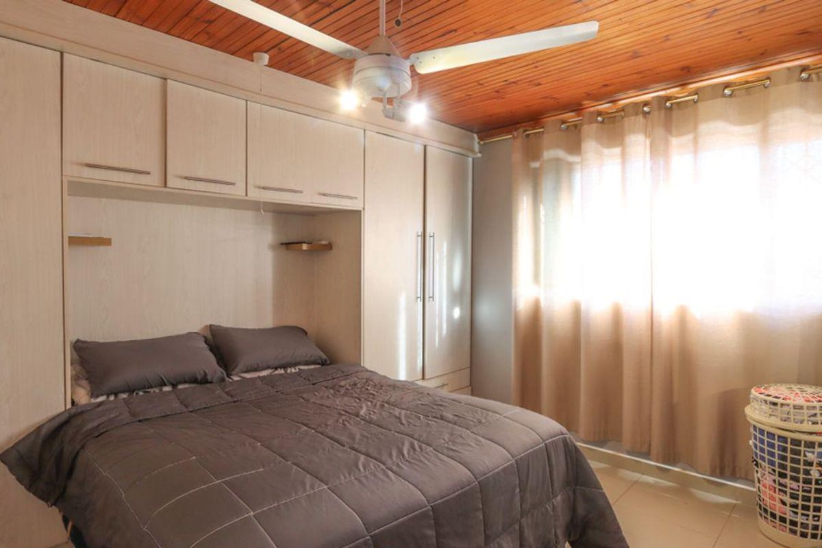 A bedroom featuring built-in cupboards, a timber ceiling, and a ceiling fan, providing functional storage and overhead lighting.
