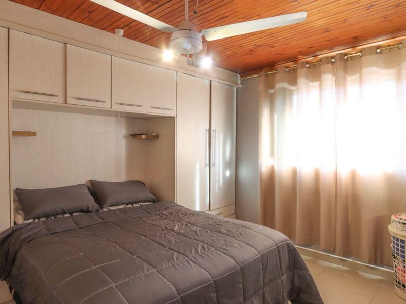 A bedroom featuring built-in cupboards, a timber ceiling, and a ceiling fan, providing functional storage and overhead lighting.