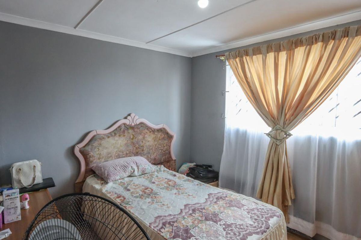 A standard bedroom featuring grey painted walls, a window with curtain treatments, and a ceiling with visible panel joints.
