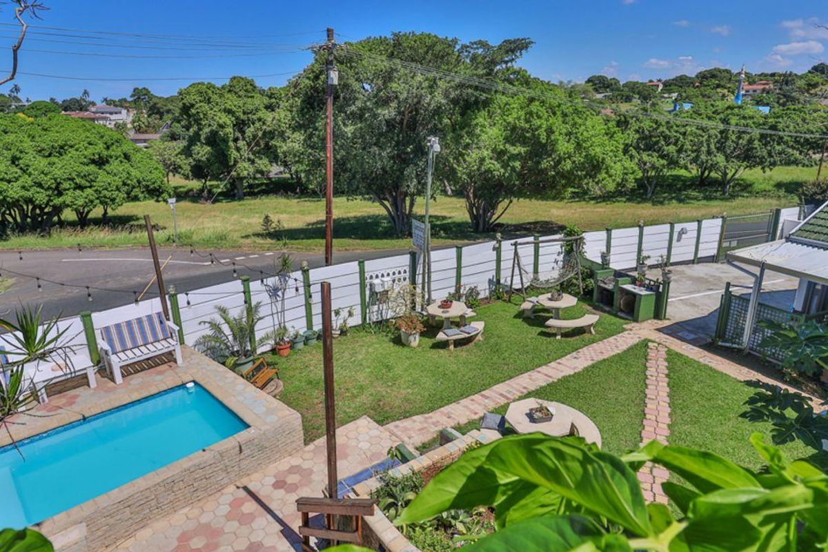 Elevated view of a private backyard featuring a swimming pool, paved pathways, lawn area, and built-in outdoor braai facility.
