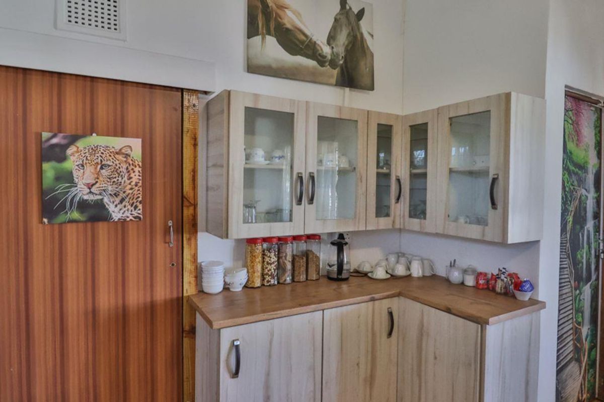 A kitchen corner featuring light wood-grain cabinetry with glass-fronted upper cupboards and a wooden countertop.