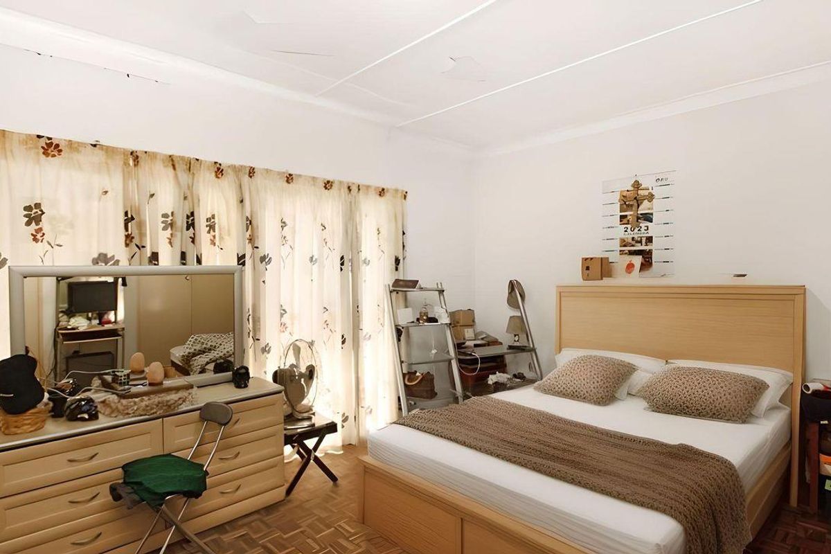 A bedroom featuring parquet flooring and large windows with curtains, providing natural light.