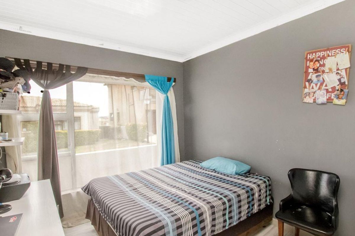 A bedroom featuring large windows, grey painted walls, and a white tongue-and-groove ceiling.