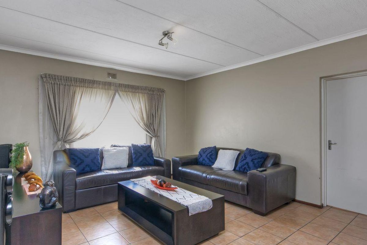 A living room featuring tiled flooring, neutral wall paint, and a standard interior door.